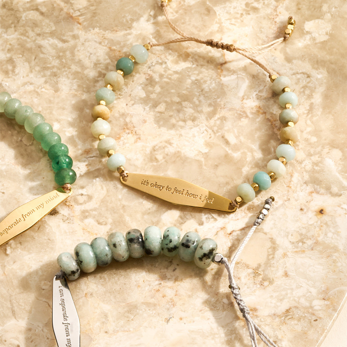Three beaded bracelets in tianshan jade, amazonite and green aventurine, featuring silver and gold accents, each designed to promote emotional well-being using principles of CBT (Cognitive Behavioral Therapy).