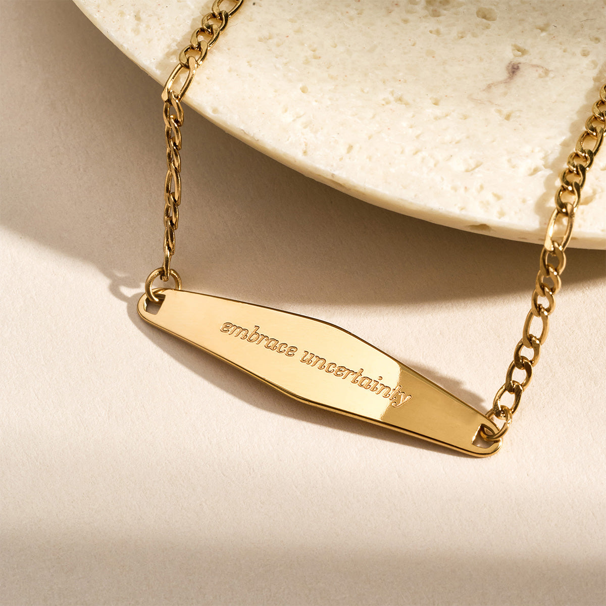 A model stacking three gold Figaro Chain Bracelets, creating a layered and stylish bracelet look.