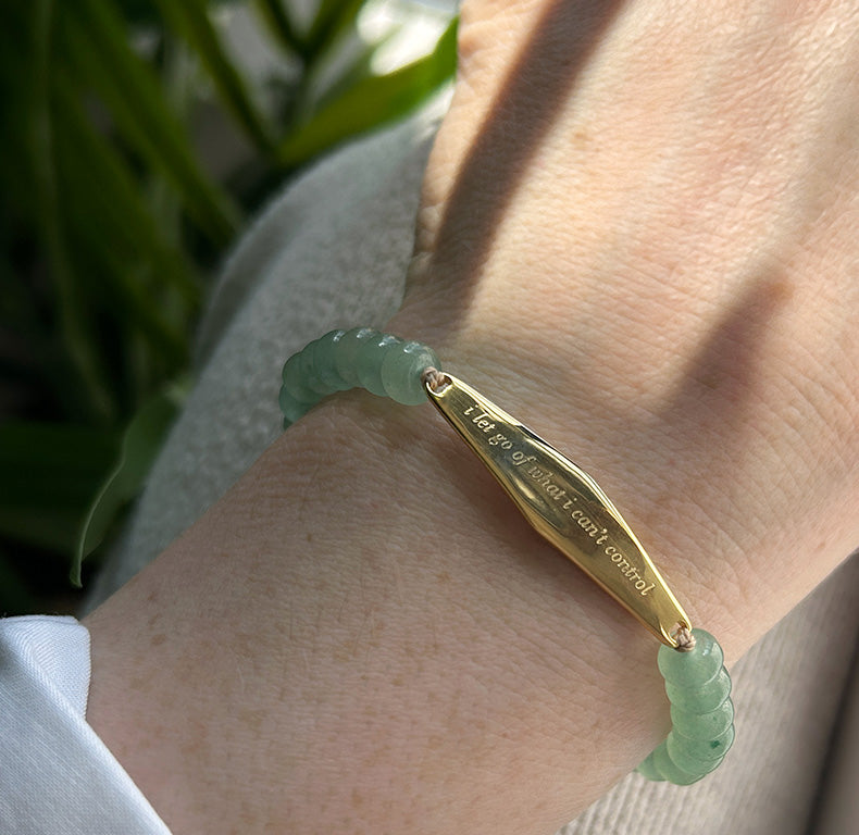 A customer wearing gold aventurine jade bracelet engraved with the phrase