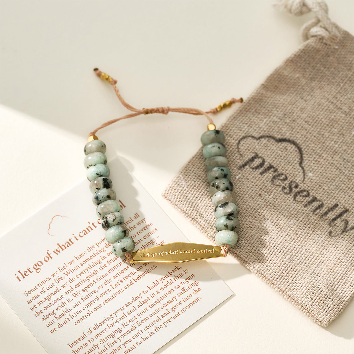 A gold Tianshan jade gemstone bracelet displayed with a Presently pouch and a phrase card engraved with