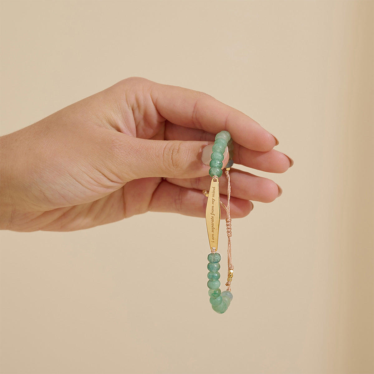 Model holding an Aventurine jade gemstone bracelet engraved with the phrase