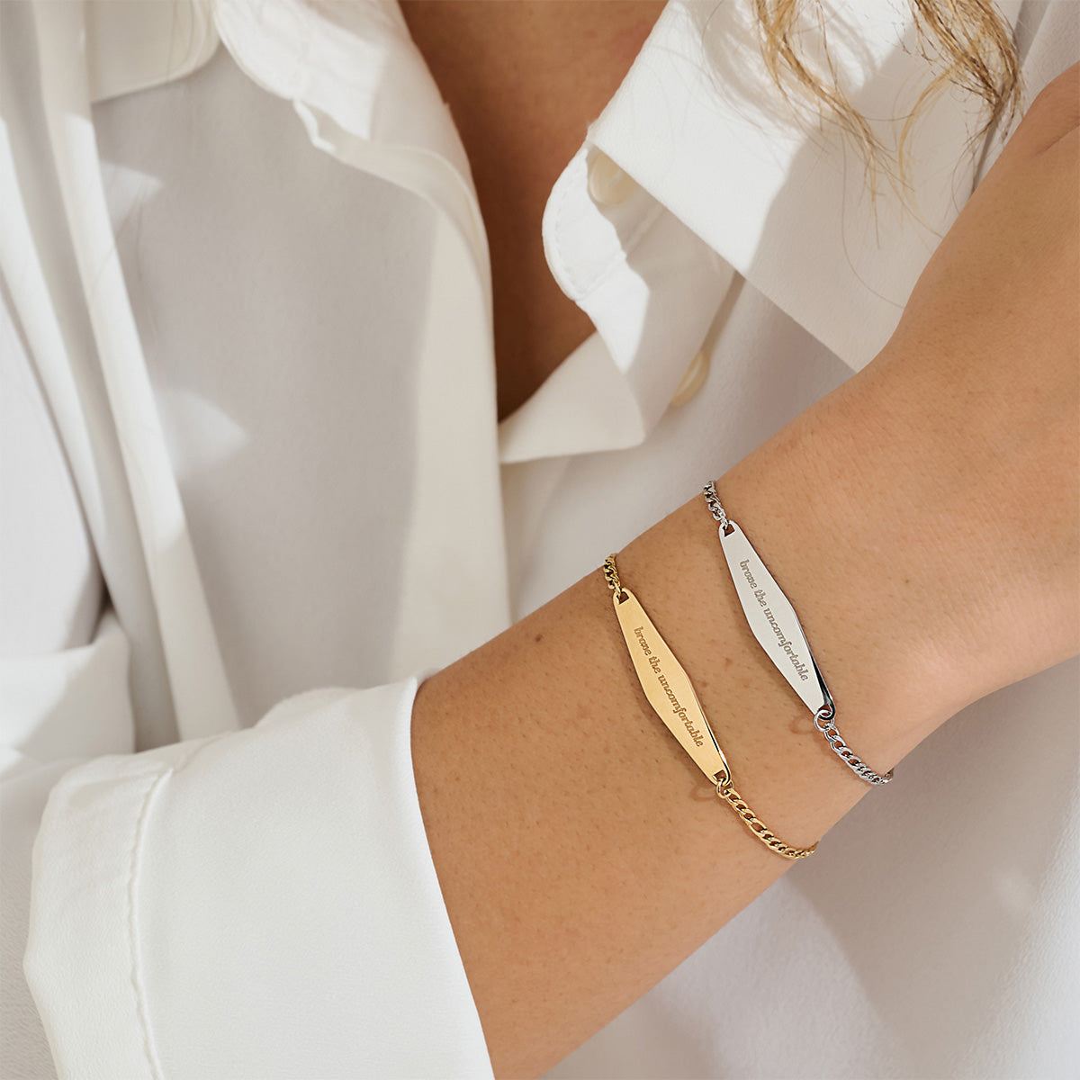 A model layering both gold and silver Figaro Chain Bracelets engraved with