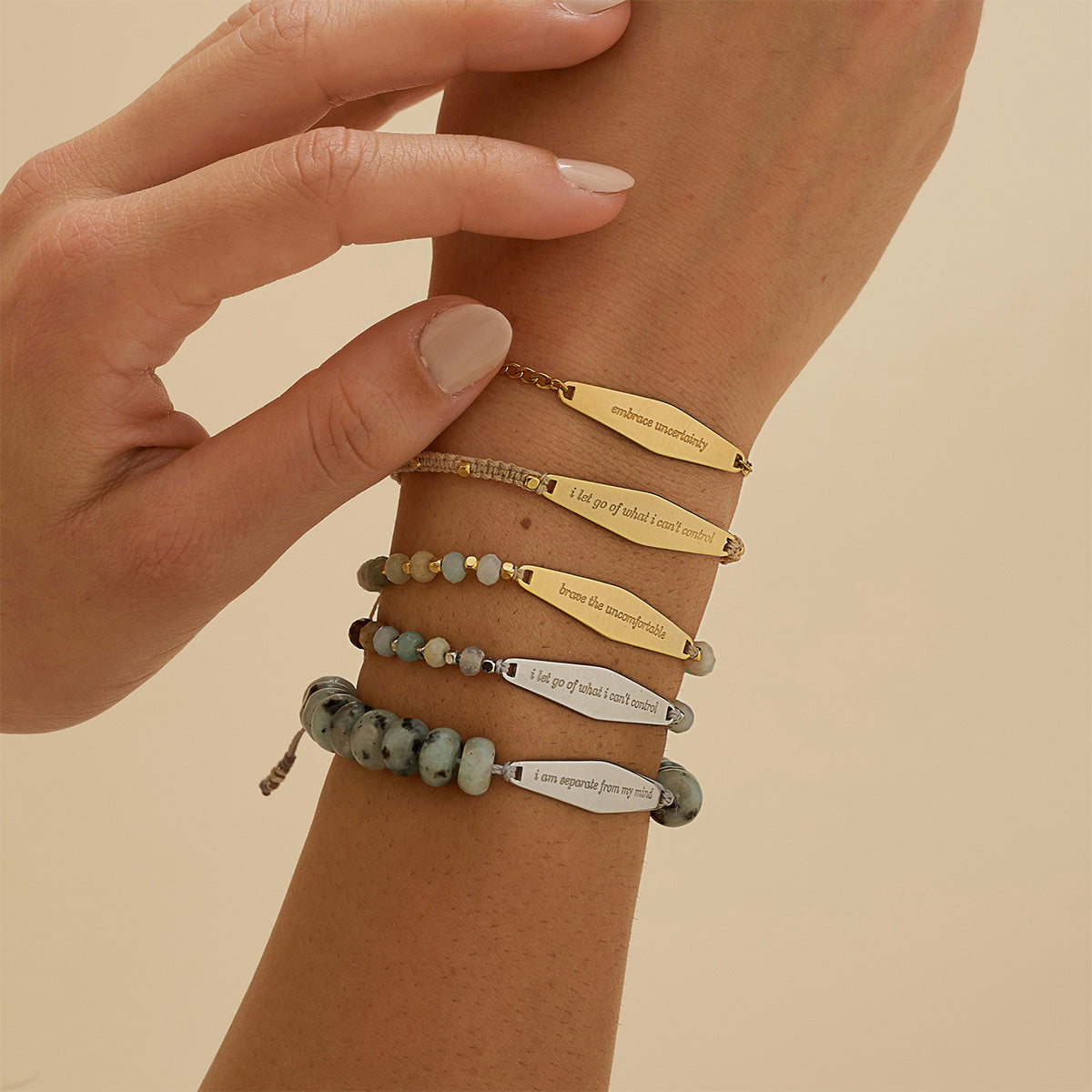 Model wears a stack of five Presently Bracelets, showcasing a mix of beaded, macrame, and chain styles, each engraved with a mental health reminder for anxiety and OCD.