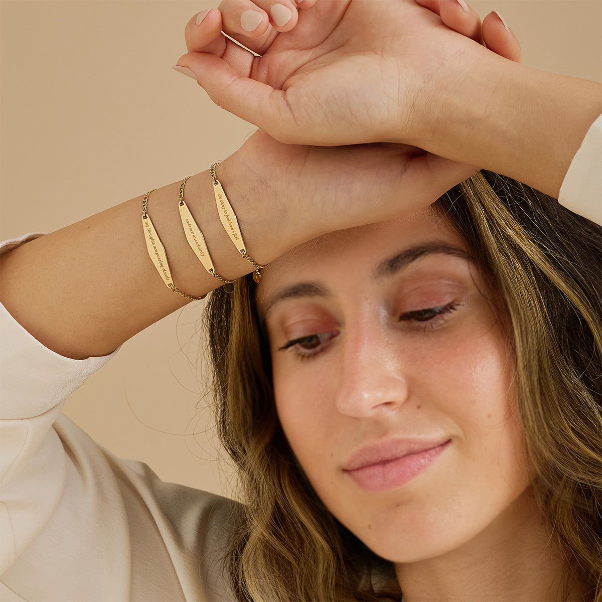 A model stacking three gold Figaro Chain Bracelets, creating a layered and stylish bracelet look.