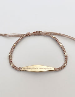 Gold Macrame Bracelet with the phrase "my thoughts are passing clouds"