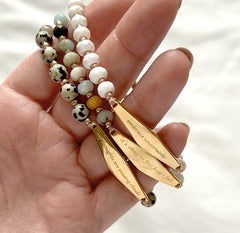 model holding three beaded bracelets from Presently’s collection, showcasing the elegant gemstone designs and engraved mindfulness reminders for anxiety and OCD support.