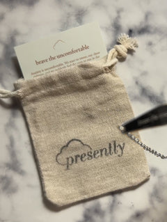 "Brave the uncomfortable" description card nestled inside a Presently Bracelets pouch, showcasing the engraved bracelet reminder for anxiety and OCD.