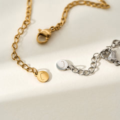 A close-up shot of the Presently Bracelets logo tag and lobster clasp, emphasizing the fine craftsmanship and branding details.