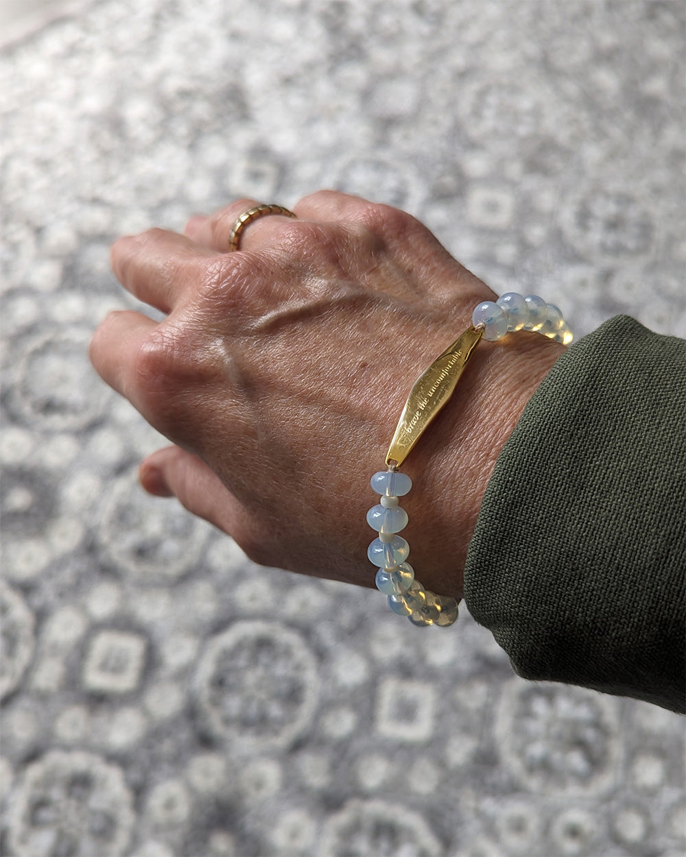 A customer wearing a Presently Opal Gemstone Bracelet, showcasing its delicate beaded design and engraved reminder. The bracelet shimmers in natural light, complementing the wearer's wrist with a meaningful touch.