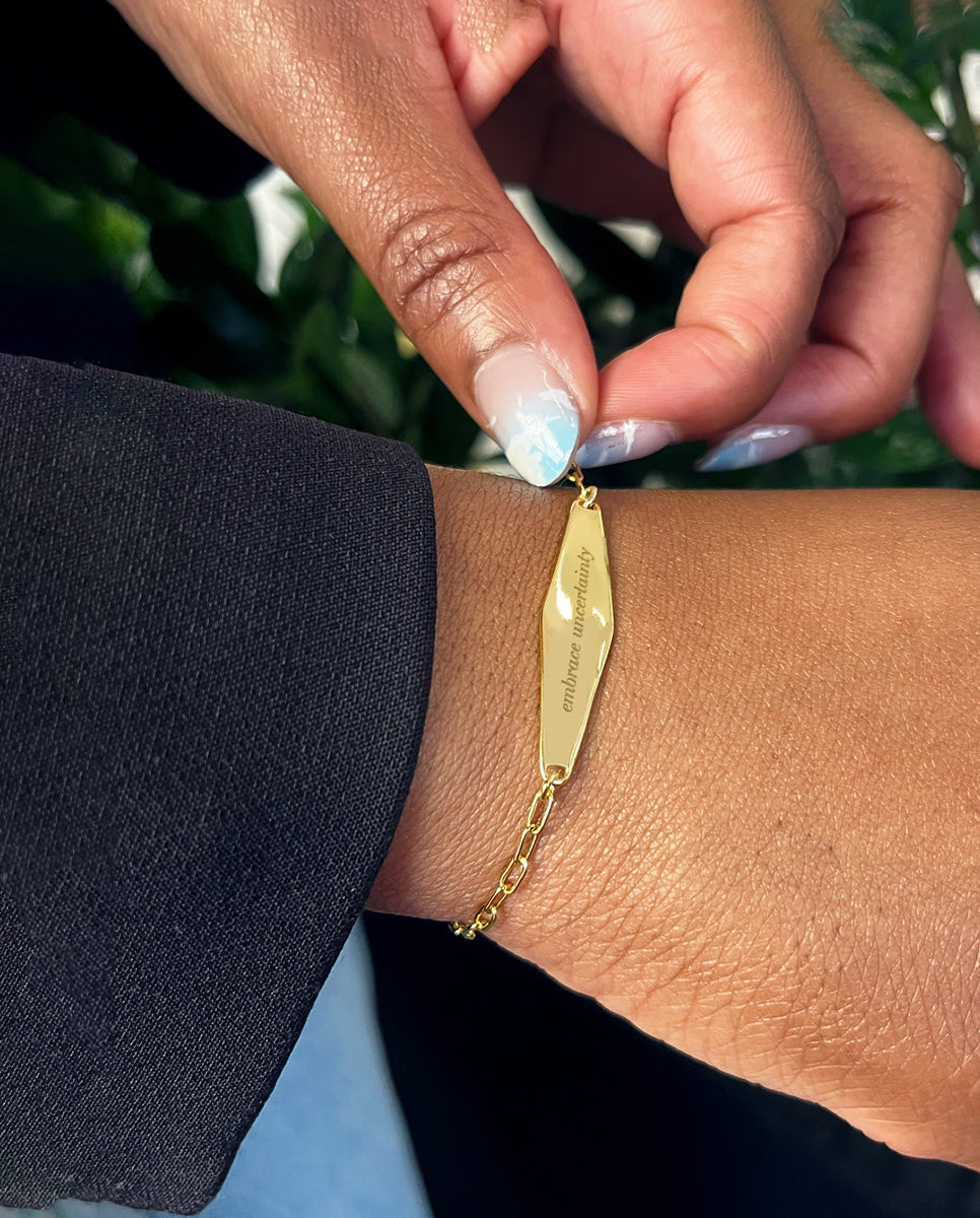 A customer wearing a gold chain bracelet engraved with 