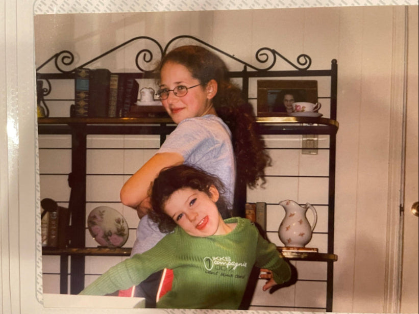 A photo of Lindsay and Emily Stetzer circa 1999, likely taken after the final pose of a dance routine performed in their living room for their brother, mom, and dad.