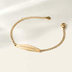 A gold Figaro Chain Bracelet with the engraved phrase "Brave the uncomfortable," showcasing its elegant chain design and motivational message.