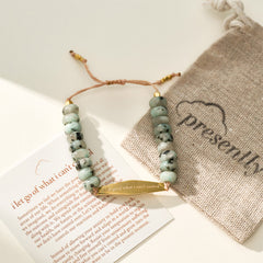A gold Tianshan jade gemstone bracelet displayed with a Presently pouch and a phrase card engraved with "I let go of what I can't control," highlighting the bracelet's connection to managing OCD and anxiety.