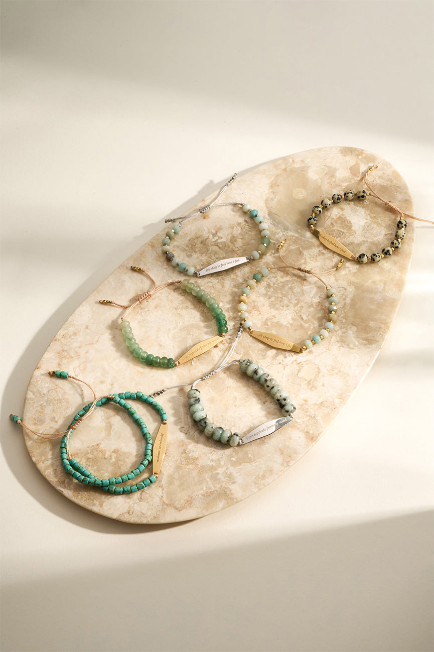 Presently Beaded Bracelet Collection displayed on a textured stone, showcasing natural gemstone colors and engraved reminders for anxiety and OCD.