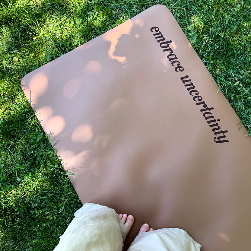 “Embrace Uncertainty” therapy-inspired yoga mat placed on grass